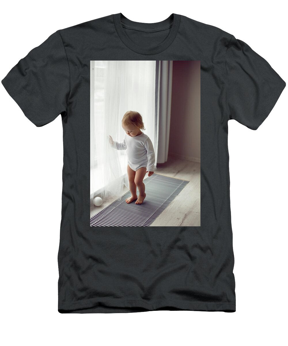 1 Child a Girl in White Clothes Stands At the Window in Winter on the Radiator Elena Saulich T-Shirt