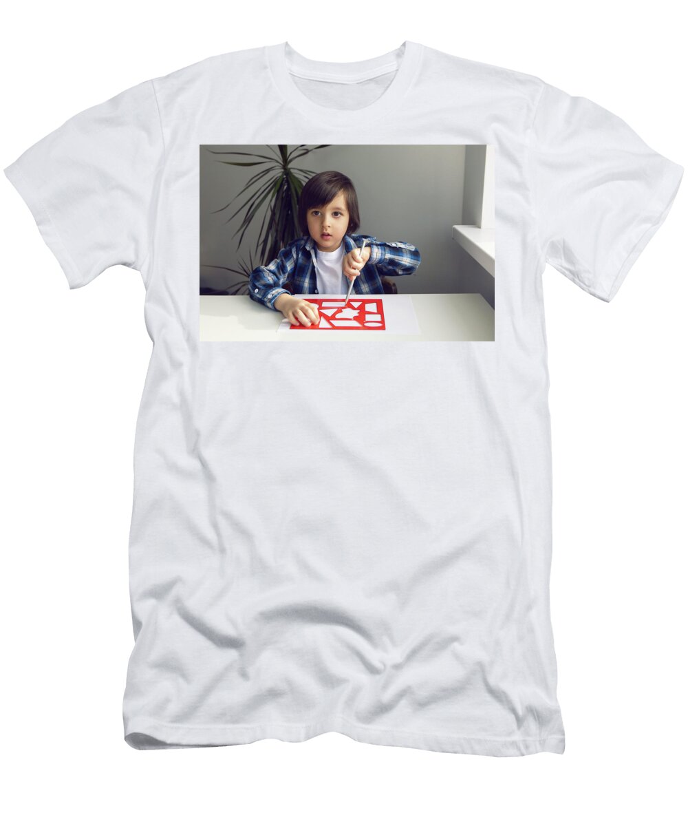 Boy Child Draws on Paper with a Ruler on a Table Sitting By the Window Elena Saulich T-Shirt
