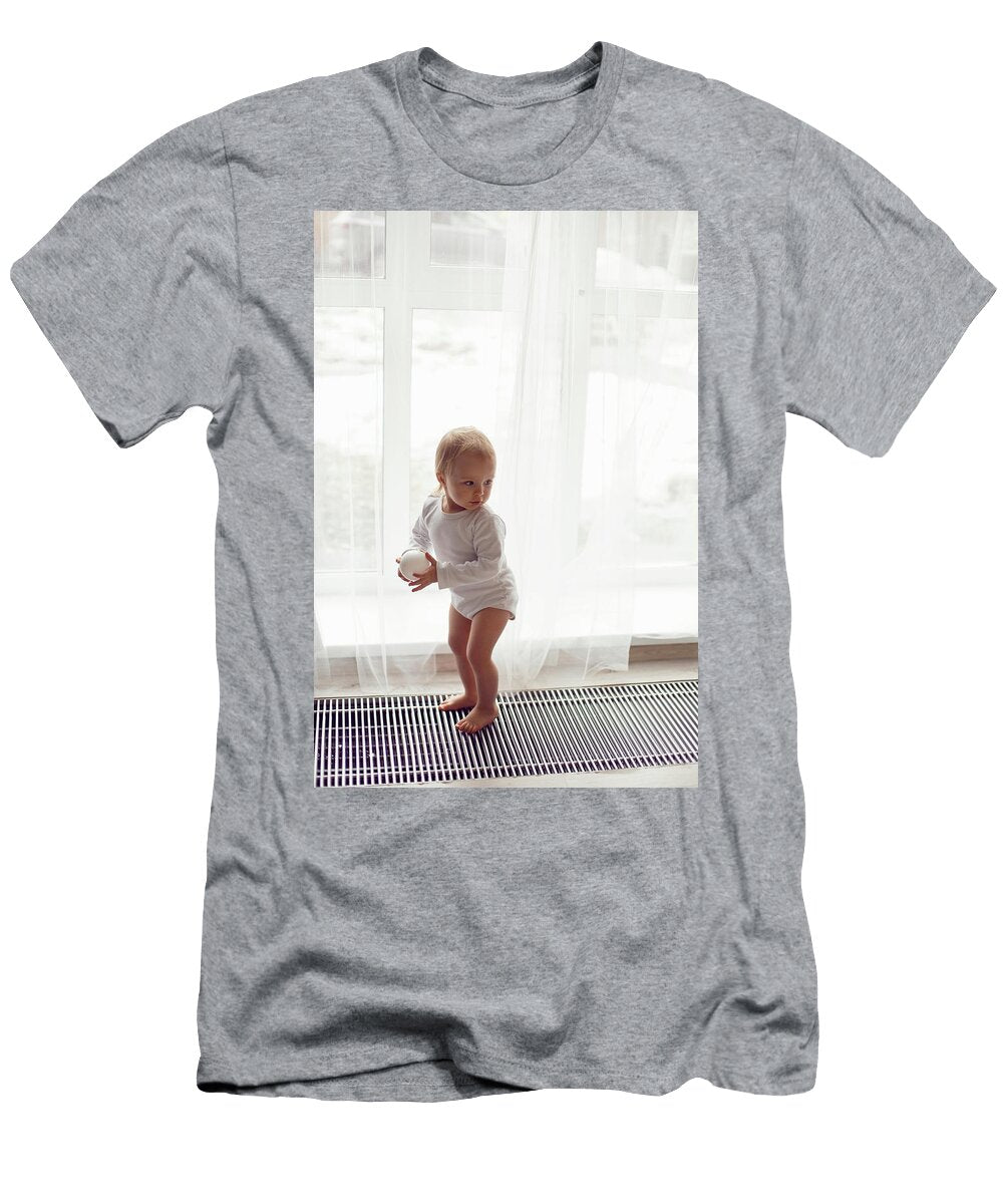 Child a Girl in White Clothes Stands At the Window in Winter on the Radiator Elena Saulich T-Shirt